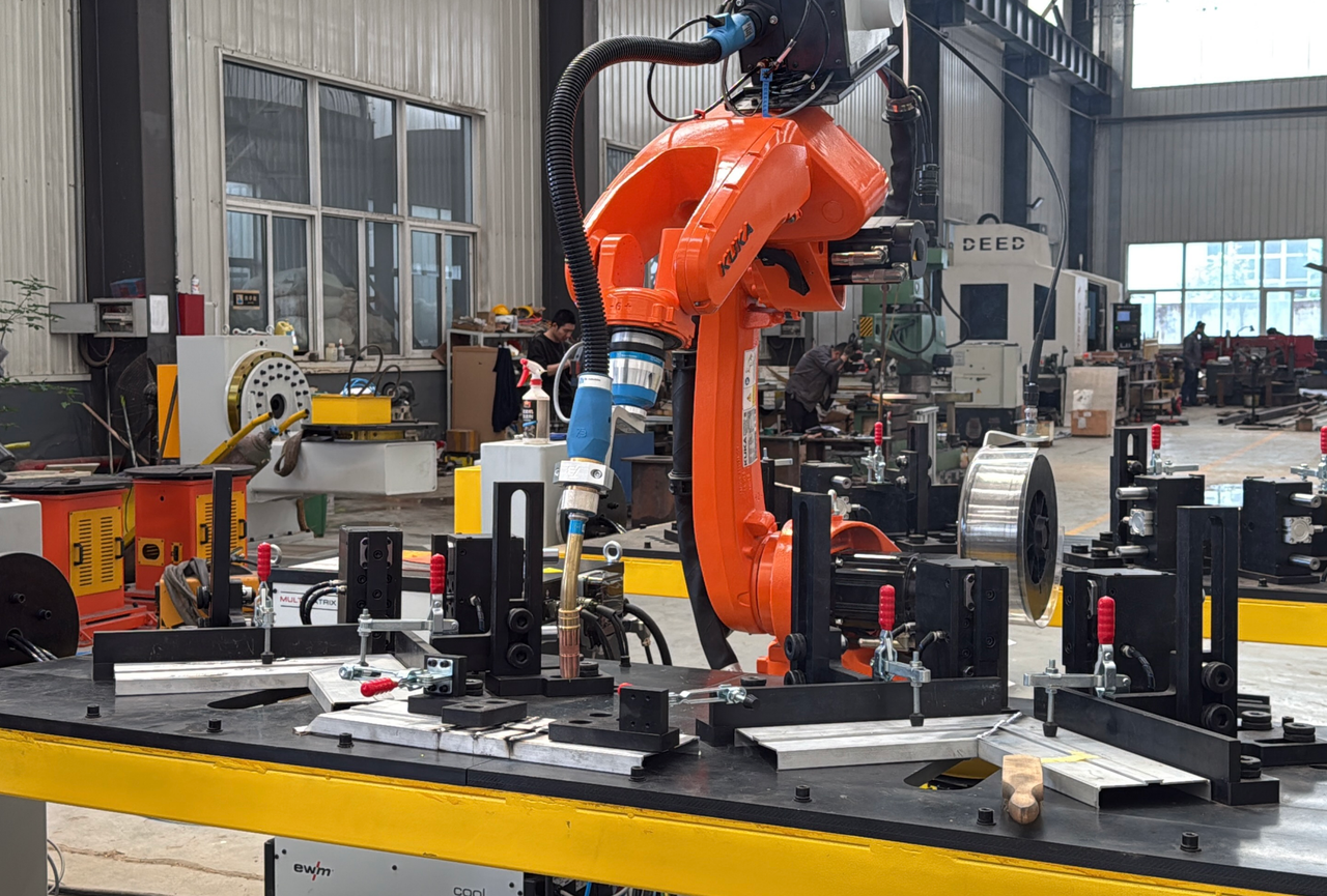 Orange industrial robot above workpiece fixtures and clamps