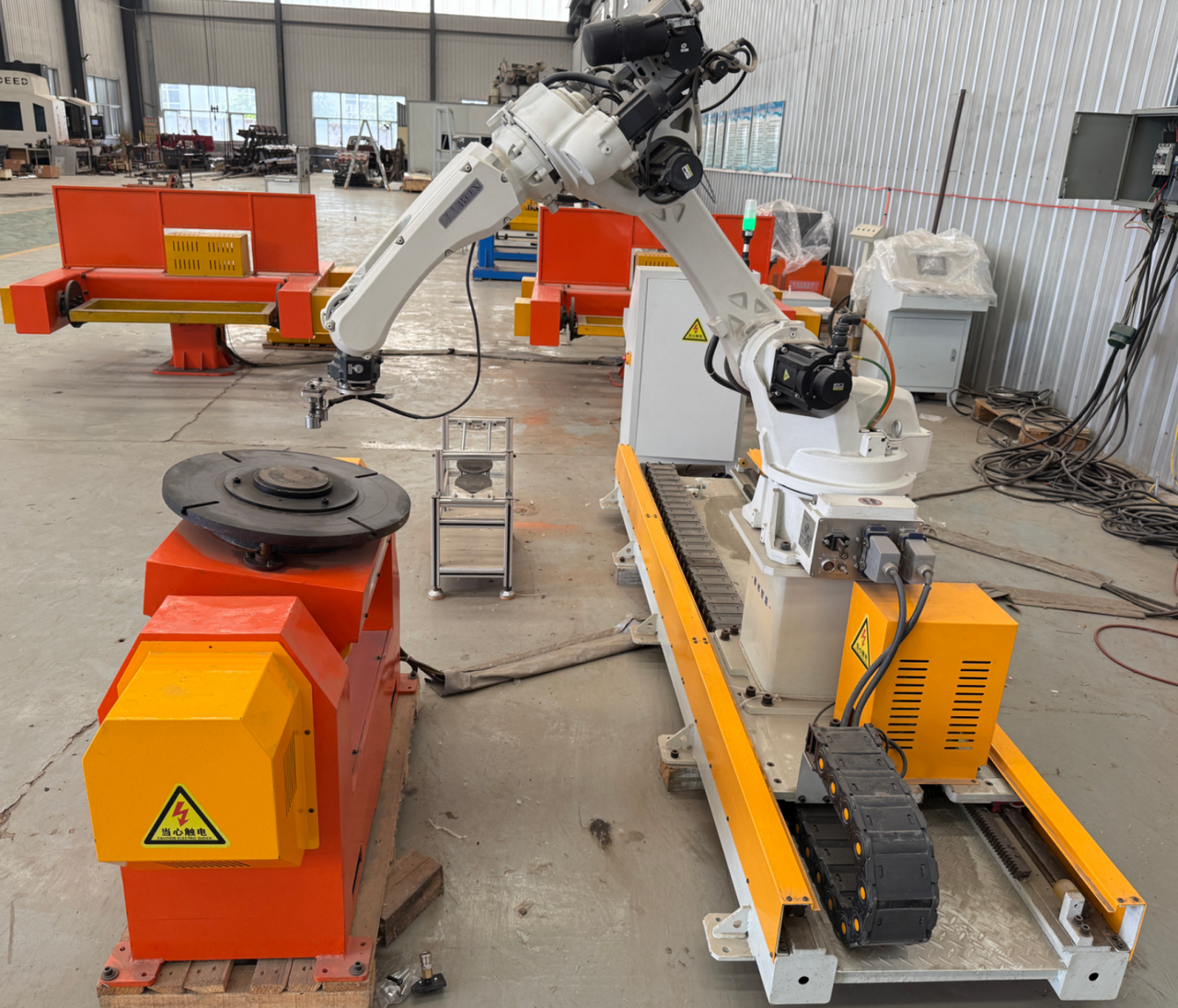 Industrial robot on a linear track beside a rotary workpiece positioner